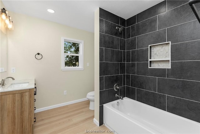 full bathroom with toilet, vanity, tiled shower / bath combo, and hardwood / wood-style flooring