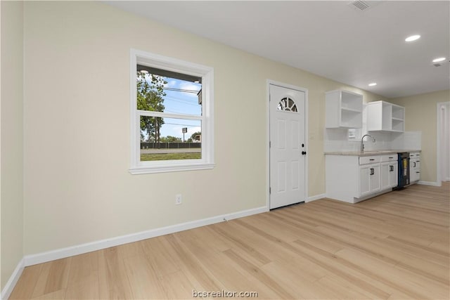 kitchen featuring decorative backsplash, beverage cooler, sink, light hardwood / wood-style flooring, and white cabinetry