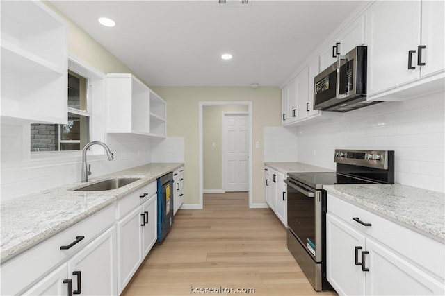 kitchen with light stone countertops, sink, light hardwood / wood-style floors, white cabinets, and appliances with stainless steel finishes