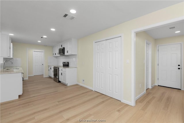 kitchen featuring backsplash, stainless steel appliances, sink, light hardwood / wood-style flooring, and white cabinetry