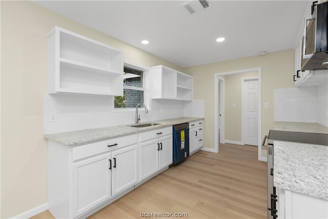 kitchen featuring sink, black dishwasher, stove, white cabinets, and light wood-type flooring