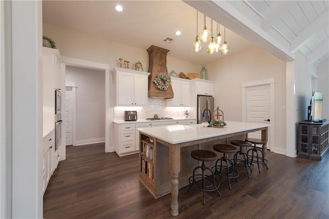 kitchen with an island with sink, dark wood-type flooring, white cabinets, and stainless steel appliances