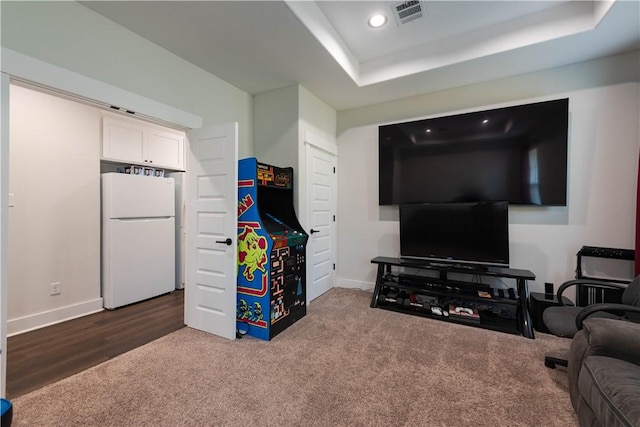 living room featuring dark hardwood / wood-style flooring and a tray ceiling