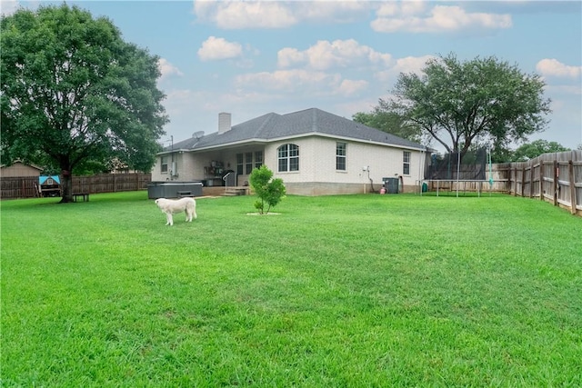 919 Alan Ln, Caldwell, TX 77836 - back of house with a trampoline, a hot tub, a fenced backyard, and a chimney