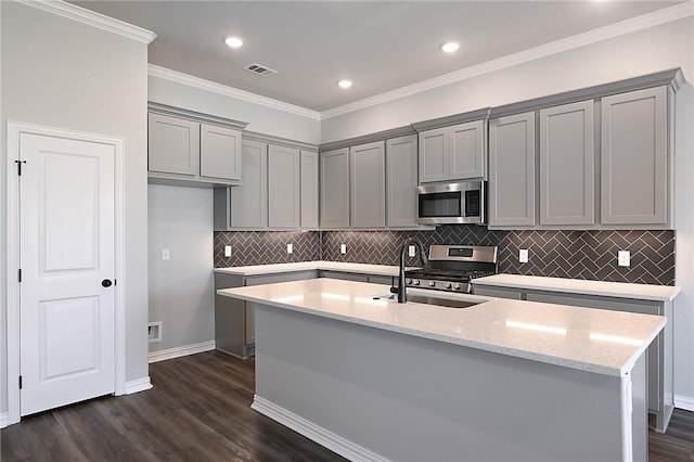 6308 Raleigh, College Station, TX 77845 - kitchen with stainless steel appliances, gray cabinets, dark wood-style floors, light stone countertops, and an island with sink