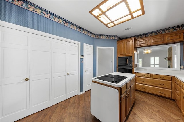 9300 Essex Grn, College Station, TX 77845 - kitchen featuring black appliances, brown cabinets, a kitchen island, and hardwood / wood-style flooring