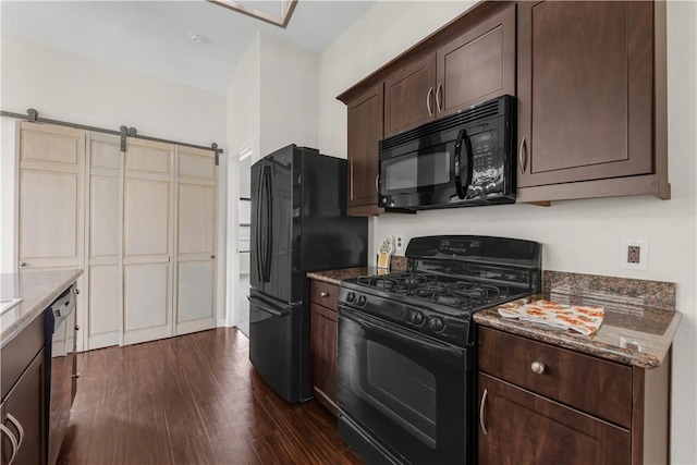 2031 Positano Loop, Bryan, TX 77808 - kitchen with black appliances, dark brown cabinetry, dark stone counters, dark wood-style floors, and a barn door