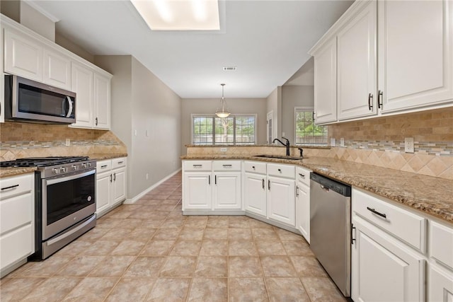 kitchen with appliances with stainless steel finishes, a sink, white cabinets, a peninsula, and backsplash