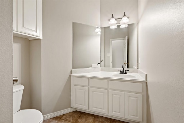 bathroom featuring toilet, vanity, tile patterned flooring, and baseboards
