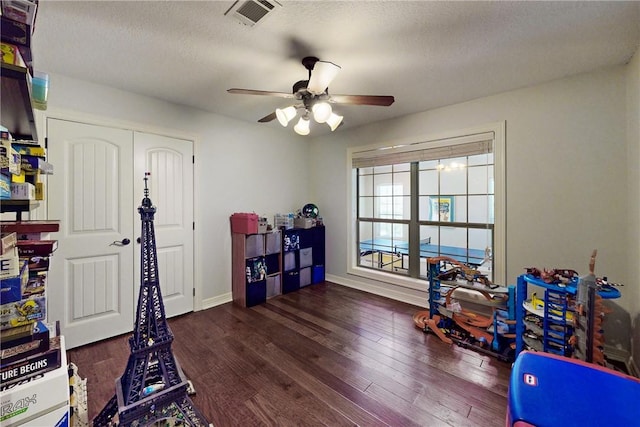 playroom featuring ceiling fan, dark hardwood / wood-style flooring, and a textured ceiling