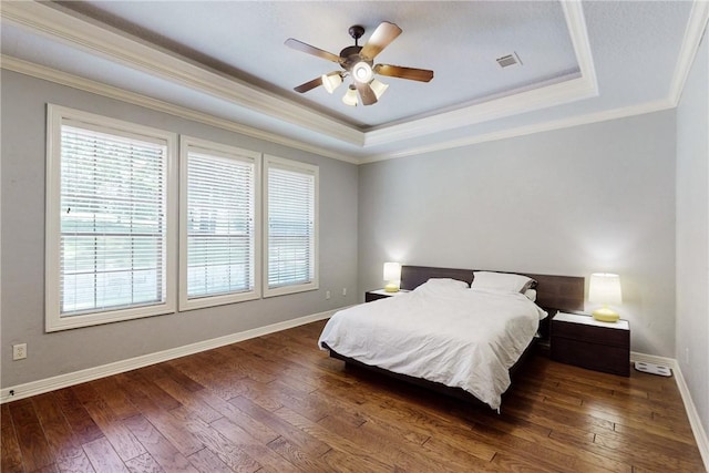 bedroom featuring a raised ceiling, ceiling fan, crown molding, and dark wood-type flooring