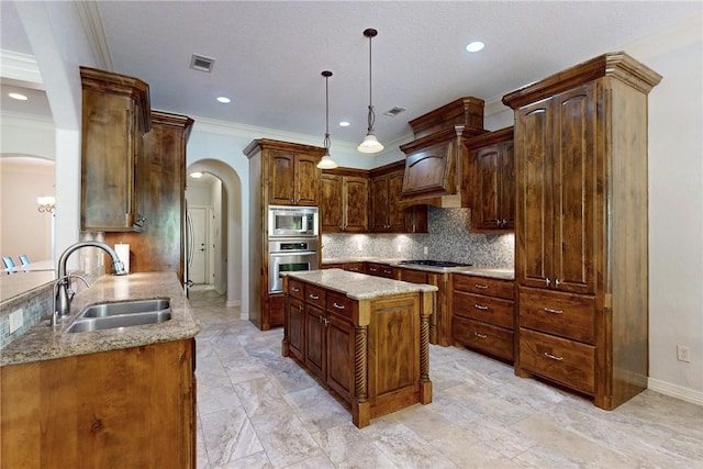 kitchen with appliances with stainless steel finishes, backsplash, sink, pendant lighting, and a kitchen island