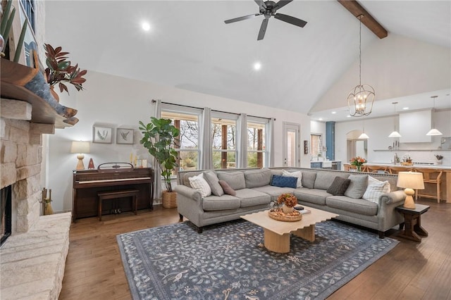 living area with a ceiling fan, wood finished floors, a fireplace, high vaulted ceiling, and beam ceiling