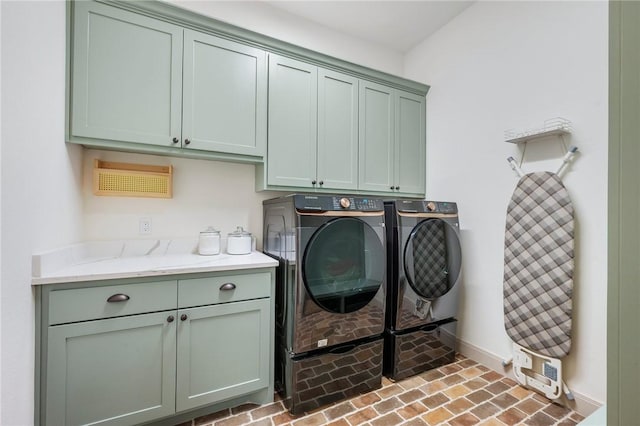 clothes washing area with brick floor, washing machine and dryer, cabinet space, and baseboards