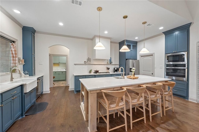 kitchen featuring visible vents, an island with sink, stainless steel appliances, light countertops, and blue cabinetry