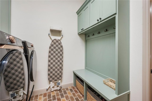 mudroom with brick floor, washing machine and dryer, and baseboards