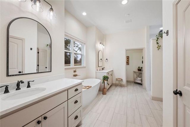 bathroom featuring baseboards, two vanities, a sink, and recessed lighting