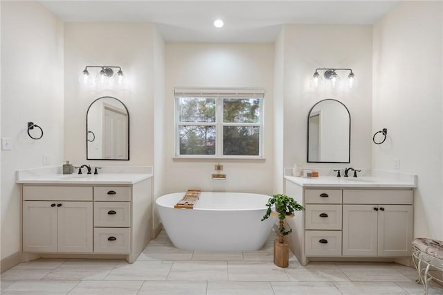 bathroom featuring a freestanding tub, two vanities, and a sink