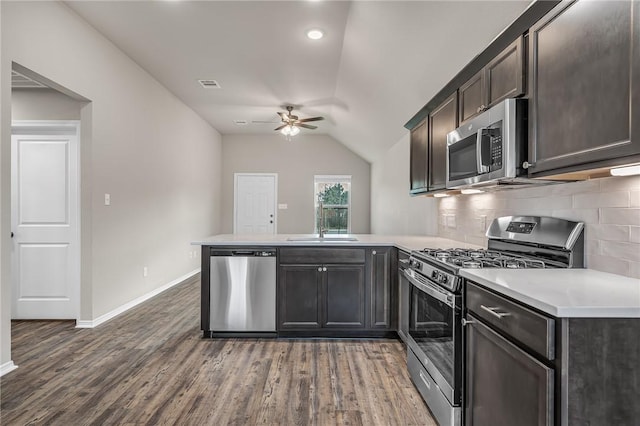 kitchen with lofted ceiling, backsplash, appliances with stainless steel finishes, dark hardwood / wood-style flooring, and kitchen peninsula