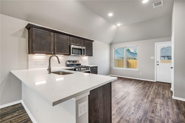 kitchen featuring kitchen peninsula, appliances with stainless steel finishes, lofted ceiling, and sink