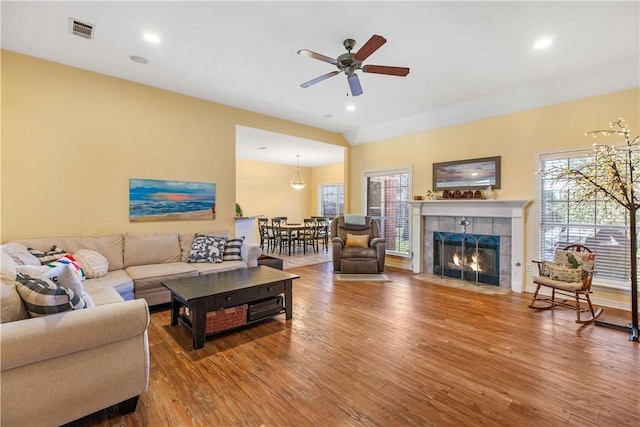 living room featuring a fireplace, wood-type flooring, and ceiling fan