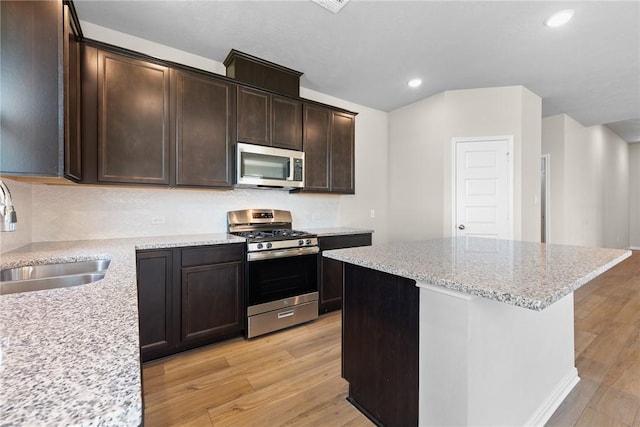 kitchen featuring sink, a kitchen island, light stone countertops, light hardwood / wood-style floors, and stainless steel appliances