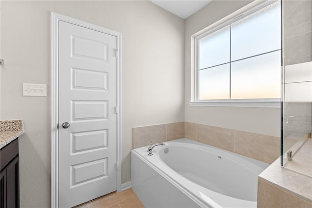 bathroom with tile patterned flooring, vanity, a tub to relax in, and plenty of natural light