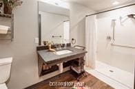 bathroom featuring wood-type flooring, toilet, walk in shower, and sink