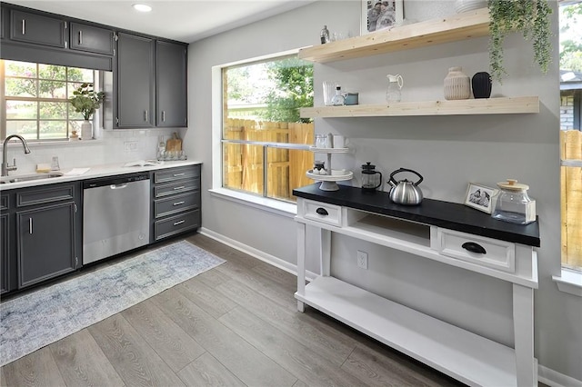 kitchen featuring dishwasher, a sink, open shelves, and wood finished floors