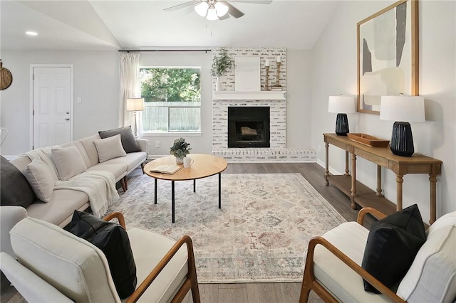 living room with a fireplace, a ceiling fan, vaulted ceiling, wood finished floors, and baseboards