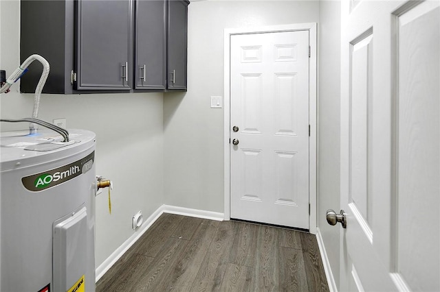 laundry room featuring dark wood finished floors, water heater, washer hookup, baseboards, and cabinet space