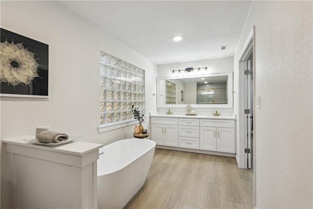 3012 Monument Dr, Round Rock, TX 78681 - bathroom featuring double vanity, a freestanding tub, wood finished floors, and recessed lighting