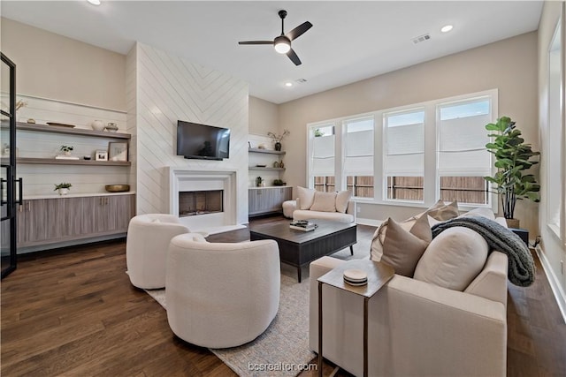 living room featuring ceiling fan, a fireplace, and dark wood-type flooring