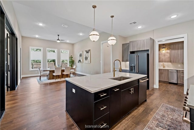 kitchen featuring ceiling fan, sink, hanging light fixtures, dark hardwood / wood-style floors, and a kitchen island with sink