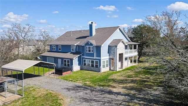 rear view of house featuring a carport, a sunroom, and a lawn