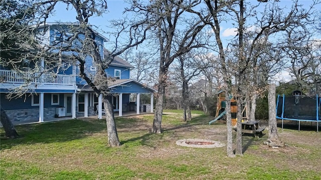 view of yard featuring a playground, a wooden deck, and a trampoline