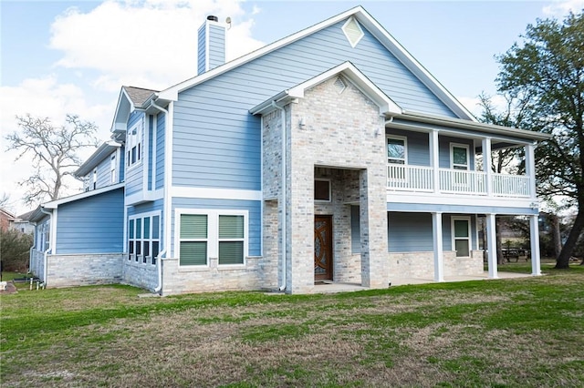 view of front of house featuring a balcony and a front lawn