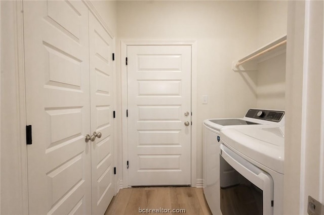 laundry area with washer and dryer and light wood-type flooring