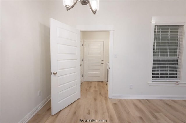 unfurnished room with a chandelier and light hardwood / wood-style floors