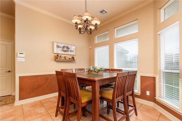 tiled dining space featuring crown molding and an inviting chandelier