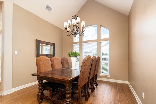 dining space with hardwood / wood-style flooring, a notable chandelier, and high vaulted ceiling