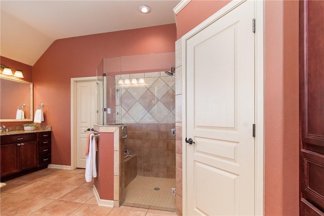 bathroom with tile patterned floors, vanity, vaulted ceiling, and walk in shower