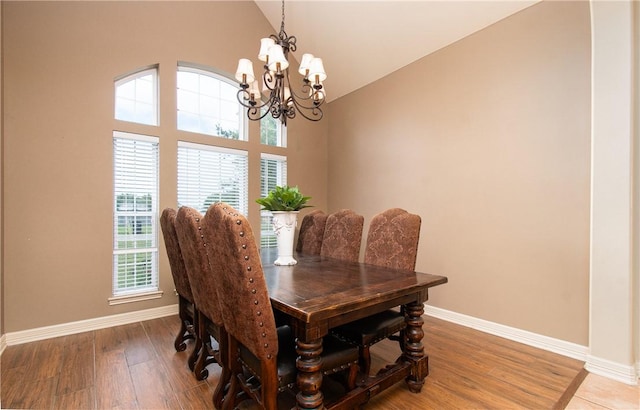 dining space with hardwood / wood-style floors, high vaulted ceiling, and a chandelier