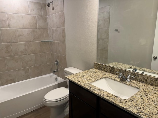 full bathroom with vanity, hardwood / wood-style flooring, toilet, and tiled shower / bath combo