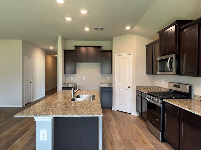 kitchen featuring stainless steel appliances, light hardwood / wood-style flooring, a kitchen island with sink, and sink