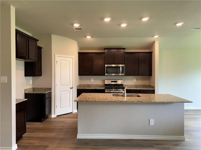 kitchen featuring dark wood-type flooring, a center island with sink, stainless steel appliances, and sink