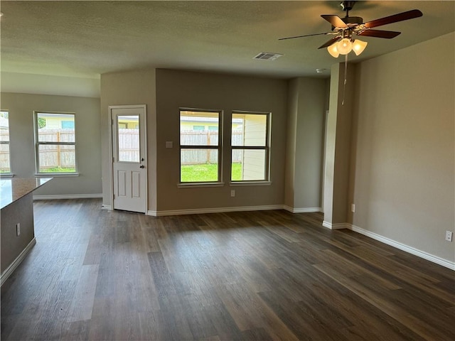 empty room with dark hardwood / wood-style floors, ceiling fan, and a textured ceiling