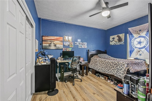 bedroom featuring ceiling fan, wood-type flooring, a closet, and a textured ceiling