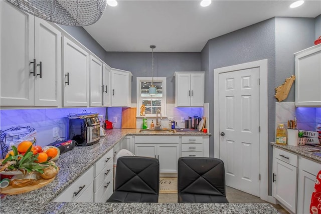 kitchen featuring white cabinetry, sink, backsplash, and decorative light fixtures