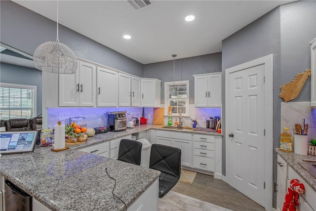 kitchen featuring sink, light hardwood / wood-style flooring, hanging light fixtures, light stone countertops, and white cabinets